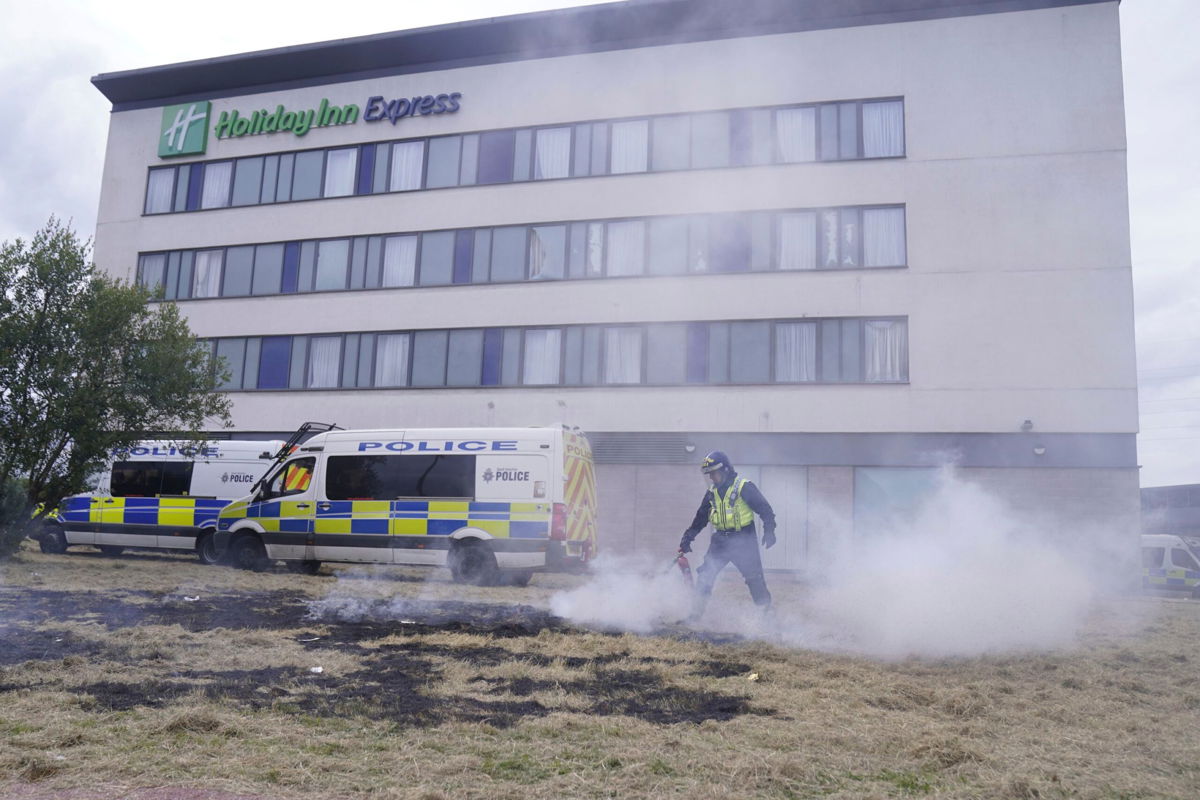 <i>Danny Lawson/Press Association/AP via CNN Newsource</i><br/>A police officer extinguishes a fire after a riot outside the Holiday Inn Express in Rotherham