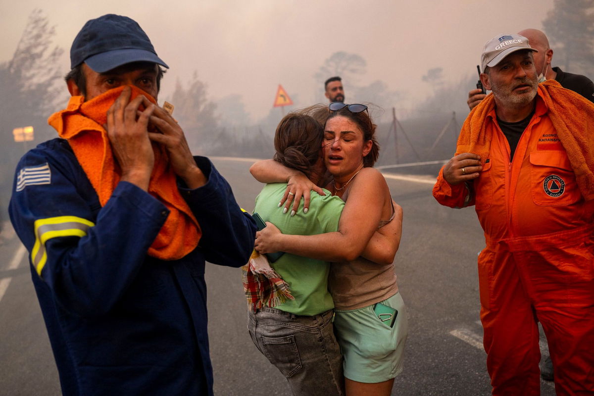 <i>Angelos Tzortzinis/AFP/Getty Images via CNN Newsource</i><br/>Emergency service personnel work to rescue people during wildfires in Varnavas