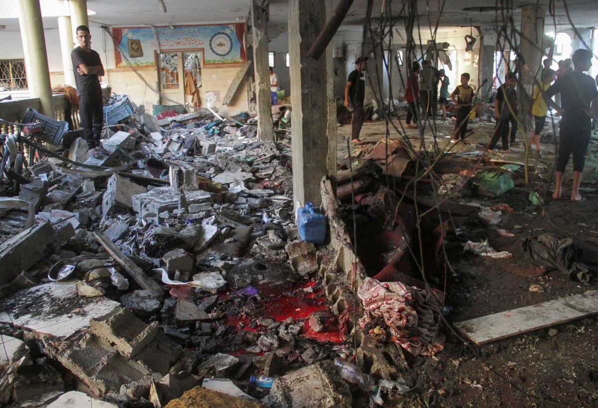 <i>Mahmoud Issa/Reuters via CNN Newsource</i><br/>Palestinians inspect the damage after an Israeli strike on a school in Gaza City on Saturday.