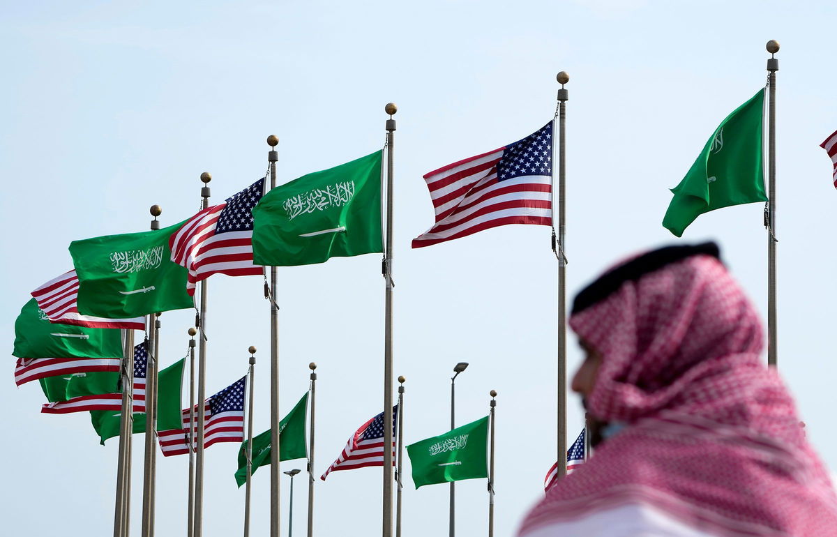 <i>Amr Nabil/AP/File via CNN Newsource</i><br/>A man stands under American and Saudi Arabian flags at a square in Jeddah