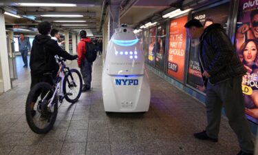 Commuters pause to look at the NYPD's Knightscope K5 autonomous security robot at the Times Square subway station in New York City.