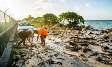 High-tide flooding and debris covers the road to the airport in the Marshall Islands capital Majuro on December 6