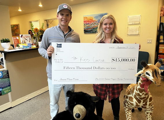 Golfer Hayden Klein presents Ginger Theis Stevens with check at KIDS Center