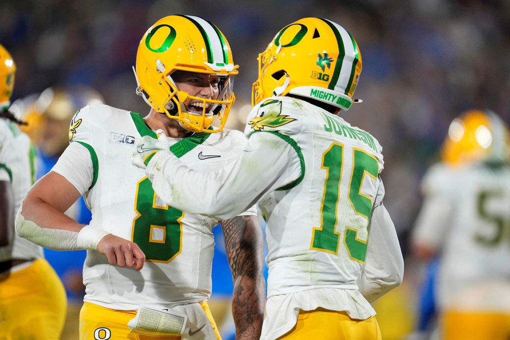 Oregon quarterback Dillon Gabriel, left, celebrates after throwing a touchdown pass to wide receiver Tez Johnson (15) during the first half of an NCAA college football game against UCLA, Saturday, Sept. 28, 2024, in Pasadena, Calif.