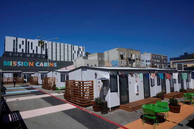 A person walks under a Mission Cabins sign at the Five Keys transitional housing location in San Francisco, Monday, Aug. 26.