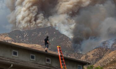 A man waters the roof of his home as the Line Fire burns in the foothills of the San Bernardino Mountains