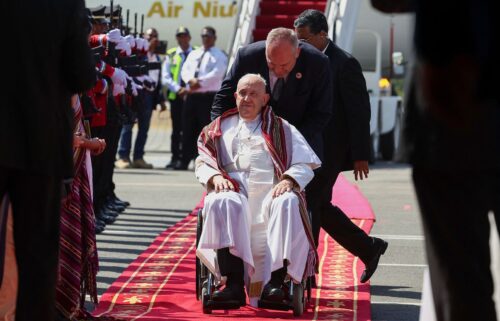 Pope Francis wears a scarf he was presented with when he arrived in Dili