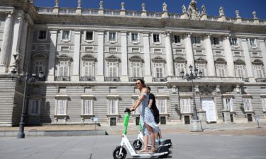 Two people ride Lime scooters near the Royal Palace in Madrid