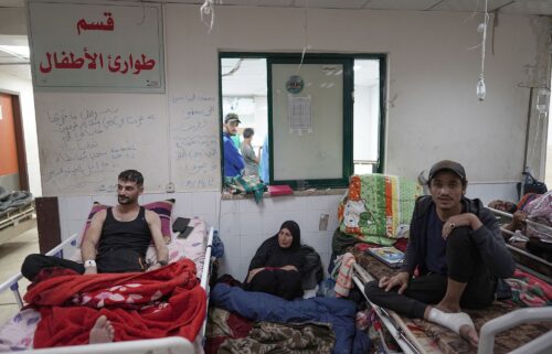 A Palestinian woman sits on the floor between patients at the Al Aqsa Martyrs Hospital in Deir Al-Balah in the central Gaza Strip on April 3.