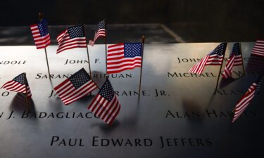 US flags are placed on the names of victims at the South Tower Memorial Pool at the National 9/11 Memorial on Independence Day In New York on July Fourth.