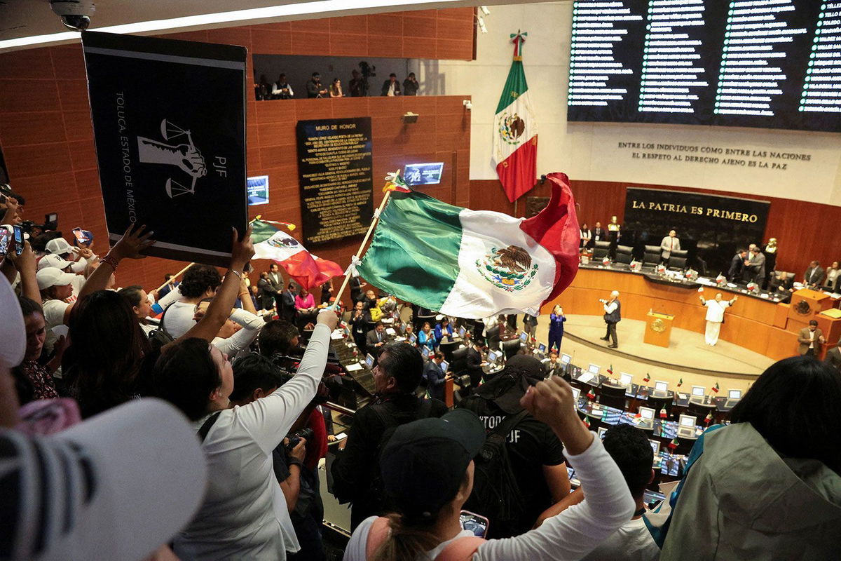 <i>Luis Cortes/Reuters via CNN Newsource</i><br/>Demonstrators wave Mexican flags after entering the Senate building in Mexico City on September 10.