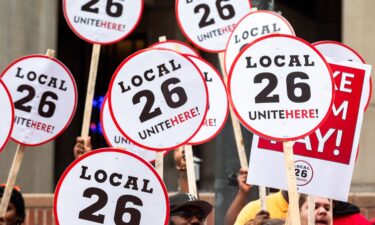 People hold UNITE HERE Local 26 signs at a press conference after a strike authorization vote by UNITE HERE Local 26 on August 8.