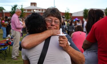 Two women embrace as students