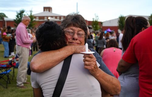 Two women embrace as students