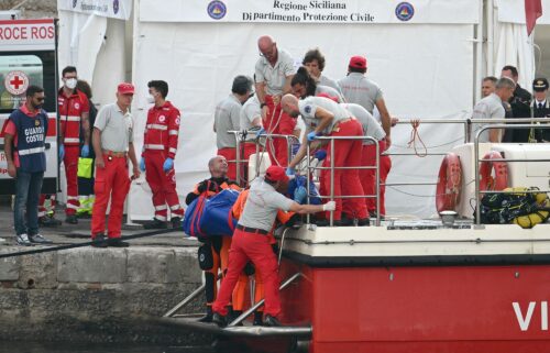 Rescuers carry a body after divers return to Porticello harbor near Palermo