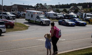 A young girl and her mother watch as law enforcement and first responders surround Apalachee High School in Winder