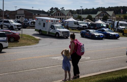 A young girl and her mother watch as law enforcement and first responders surround Apalachee High School in Winder