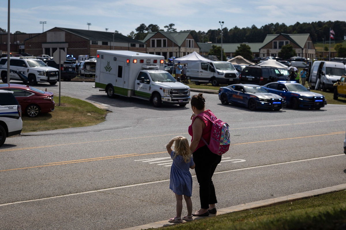 <i>Christian Monterrosa/AFP/Getty Images via CNN Newsource</i><br/>A young girl and her mother watch as law enforcement and first responders surround Apalachee High School in Winder