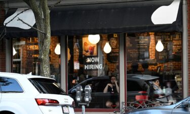 A "Now Hiring" sign advertising job openings is viewed in the window of a cafe on July 8 in Boston. Even though the unemployment rate edged lower last month to 4.2%