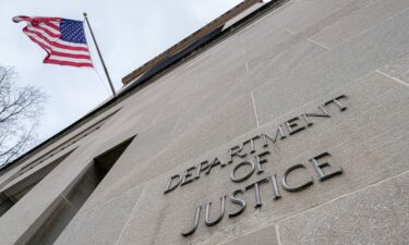 The US Flag flies above a sign marking the US Department of Justice headquarters building on January 20