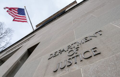 The US Flag flies above a sign marking the US Department of Justice headquarters building on January 20