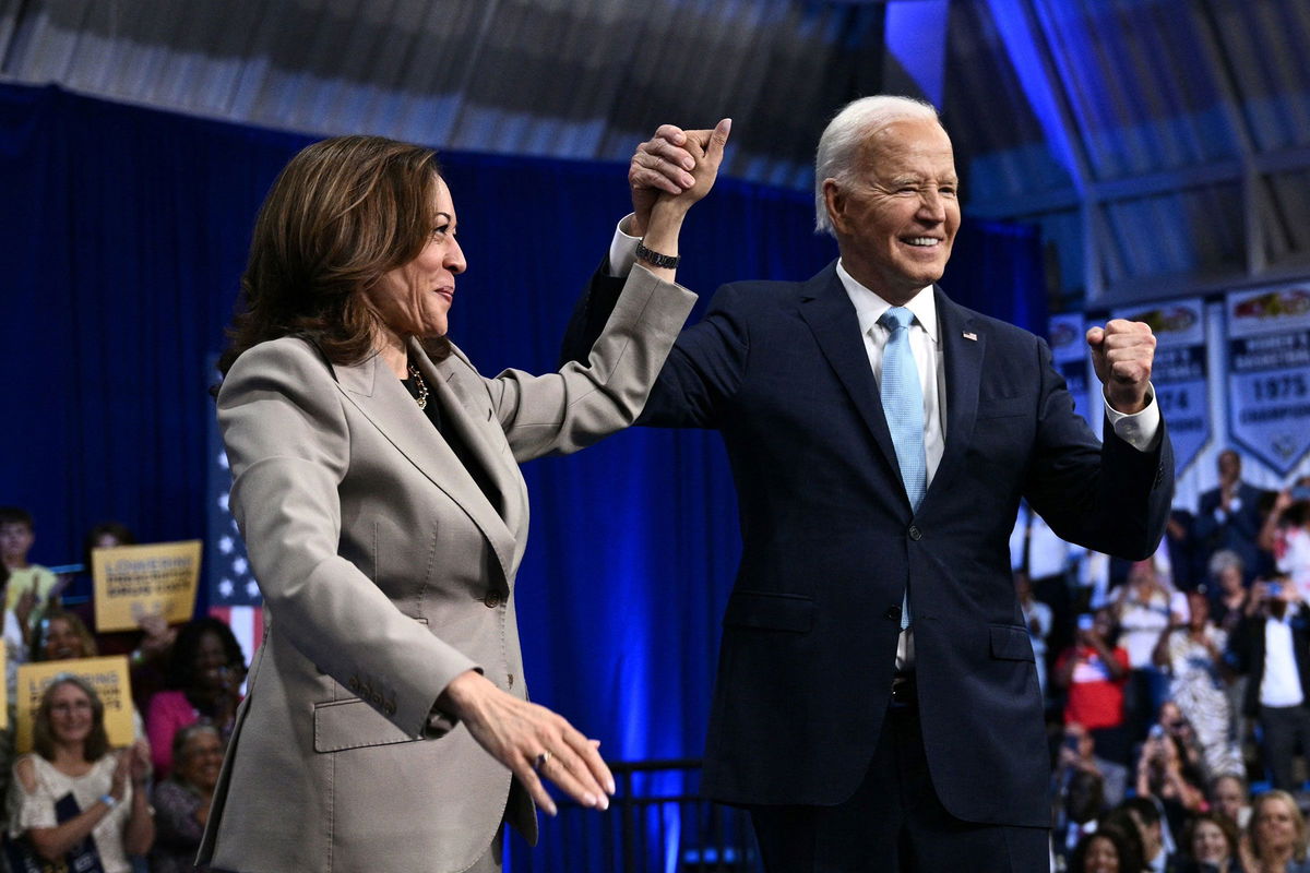 <i>Brendan Smialowski/AFP/Getty Images via CNN Newsource</i><br/>President Joe Biden and Vice President Kamala Harris clasp and raise their hands after speaking at Prince George's Community College in Largo