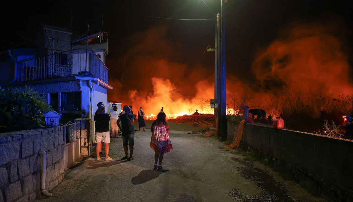 <i>Pedro Nunes/Reuters via CNN Newsource</i><br/>People watch a wildfire in Canas de Senhorim