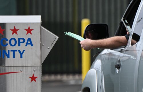 A driver uses a smartphone as they drop off multiple ballots into a ballot drop box for early voting outside of the Maricopa County Tabulation and Election Center ahead of the Arizona midterm elections in Phoenix