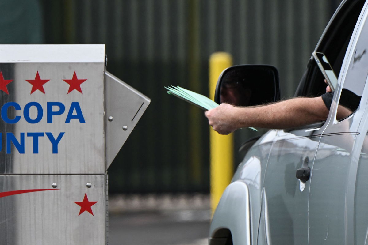 <i>PATRICK T. FALLON/AFP/AFP via Getty Images via CNN Newsource</i><br/>A driver uses a smartphone as they drop off multiple ballots into a ballot drop box for early voting outside of the Maricopa County Tabulation and Election Center ahead of the Arizona midterm elections in Phoenix