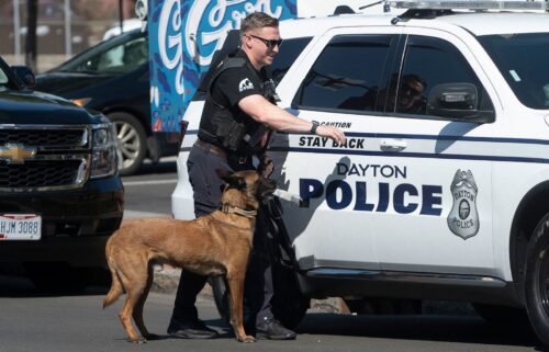 A police officer and his dog return to their vehicle after sweeping the Springfield City Hall grounds for explosives after bomb threats on September 12.