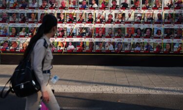 A woman walks next to a wall of posters of hostages kidnapped during the deadly October 7 attack on Israel by Hamas