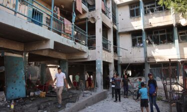 Palestinians inspect the damage at the site of the Israeli strike.