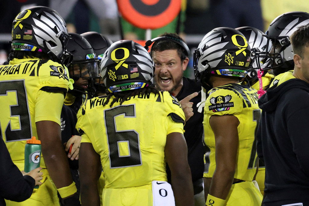 Oregon head coach Dan Lanning, center, talks to his players during a timeout in the first half of an NCAA college football game against Michigan State, Friday, Oct. 4, 2024, in Eugene.