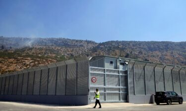 An Albanian walks in front of the main gate talking on a radio at an Italian-run migrant center located within an old military camp in Gjader