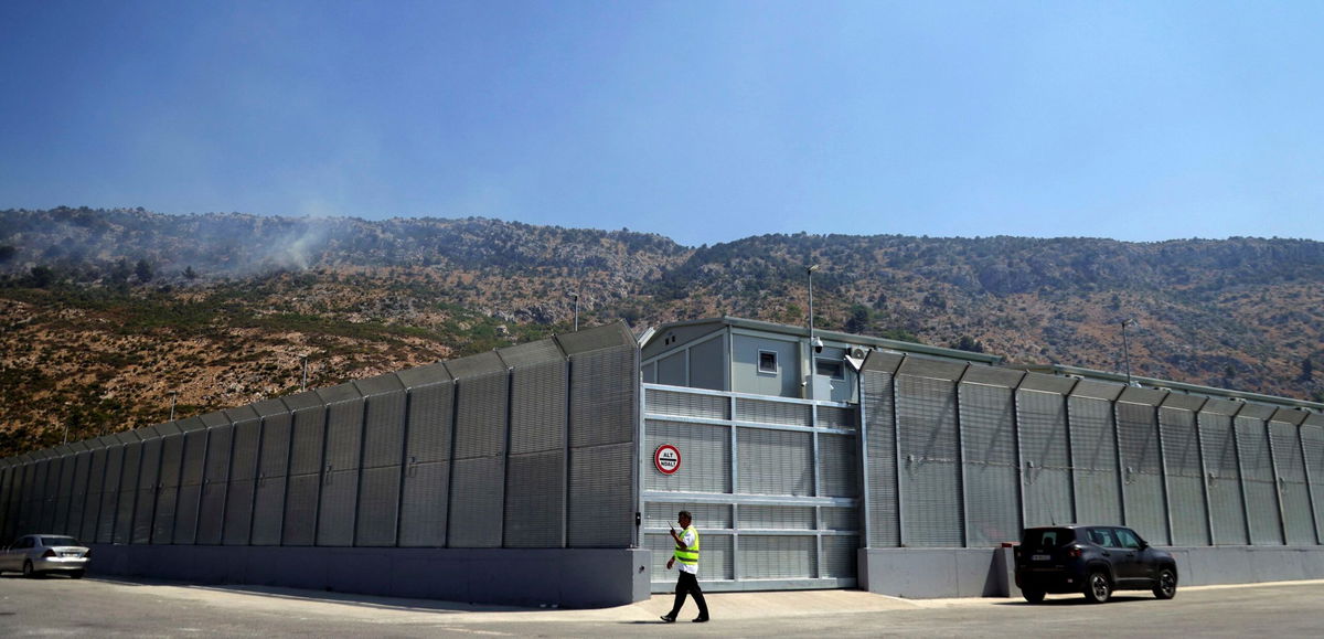 <i>Adnan Beci/AFP/Getty Images via CNN Newsource</i><br/>An Albanian walks in front of the main gate talking on a radio at an Italian-run migrant center located within an old military camp in Gjader