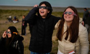 People watch as an annular solar eclipse appears Wednesday in the sky over Puerto San Julián