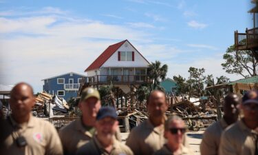 First responders watch President Joe Biden's motorcade against the backdrop of damaged properties in Keaton Beach