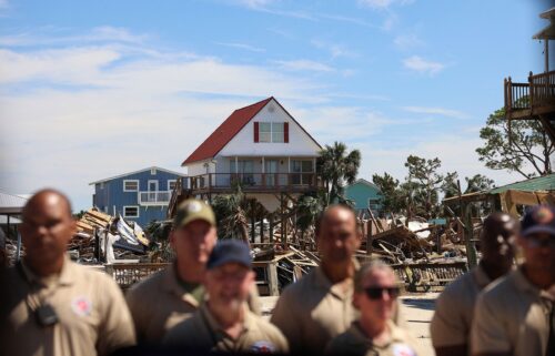 First responders watch President Joe Biden's motorcade against the backdrop of damaged properties in Keaton Beach