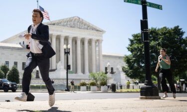 A journalist runs across the US Supreme Court plaza carrying an opinion to a news correspondent as the court handed down decisions on July 1 in Washington