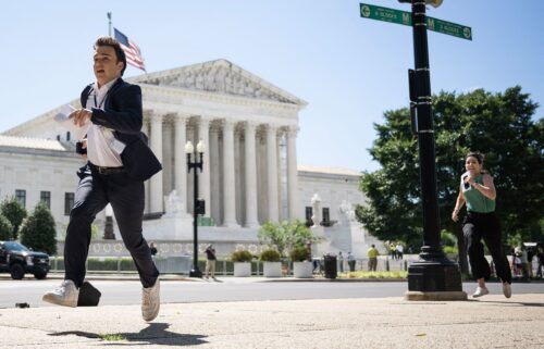 A journalist runs across the US Supreme Court plaza carrying an opinion to a news correspondent as the court handed down decisions on July 1 in Washington