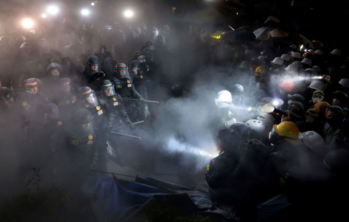 <i>Wally Skalij/Los Angeles Times/Getty Images via CNN Newsource</i><br/>Police officers clash with pro-Palestinian protesters as a fire extinguisher is deployed at UCLA in Los Angeles