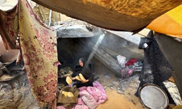 A Palestinian woman holds pita bread in a makeshift tent in Khan Younis