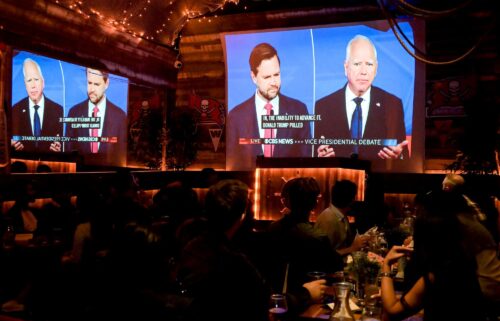 Sen. JD Vance and Gov. Tim Walz are shown on screen during a vice presidential debate watch party in New York on October 1.