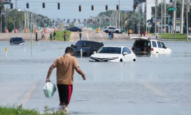 A young man walks past flooded vehicles in Tampa