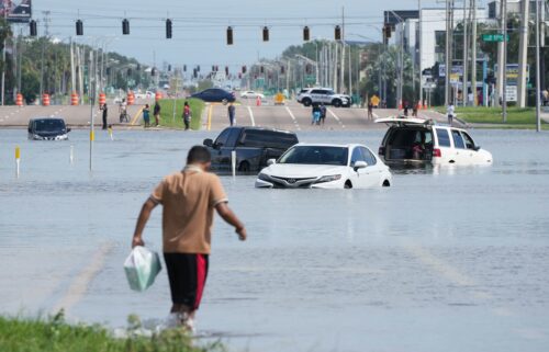 A young man walks past flooded vehicles in Tampa