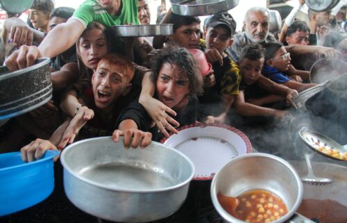 Palestinians receive food cooked by a charity kitchen in northern Gaza