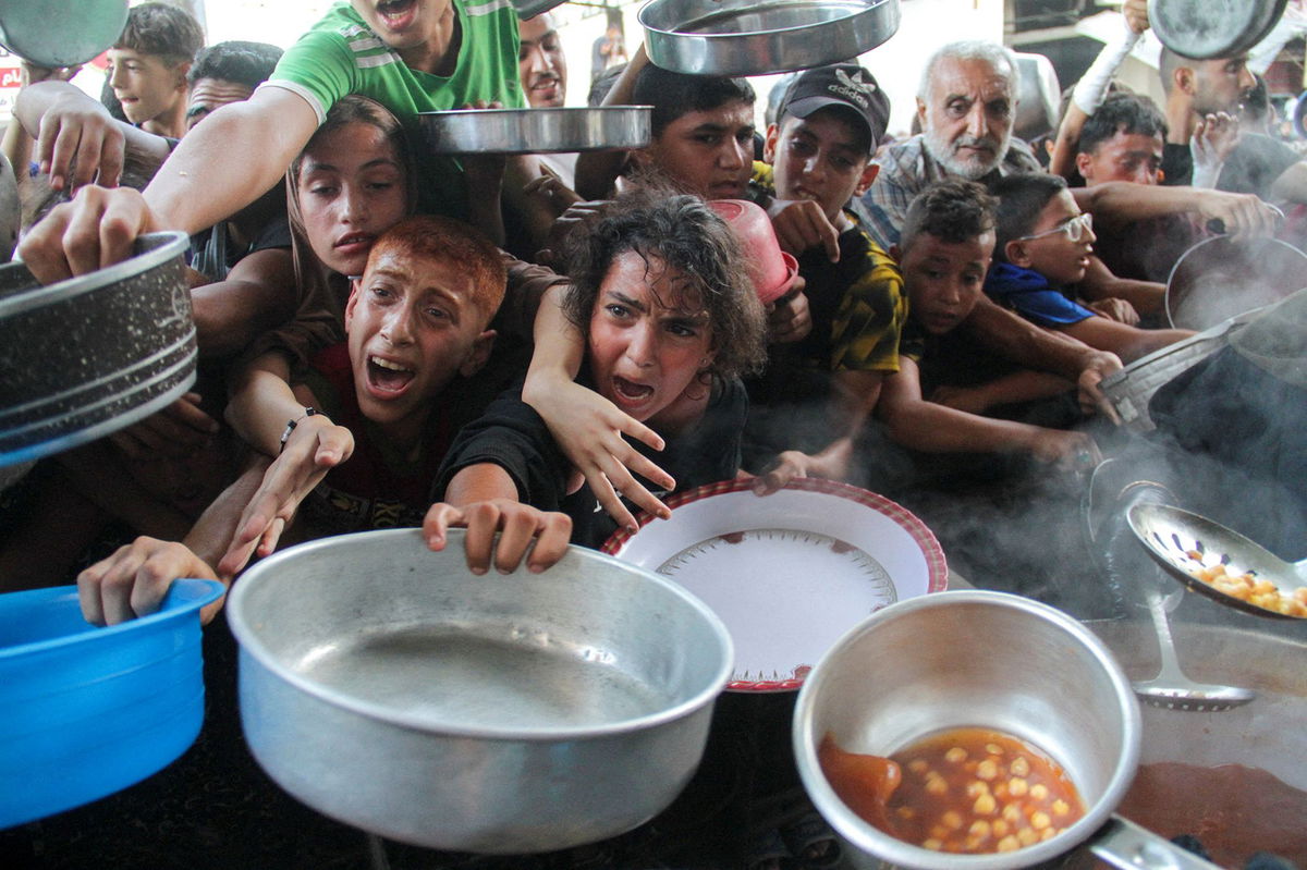 <i>Mahmoud Issa/Reuters via CNN Newsource</i><br/>Palestinians receive food cooked by a charity kitchen in northern Gaza