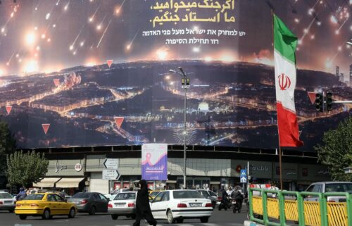 People walk on the streets of Tehran where Iranian flags and Hezbollah banners are seen