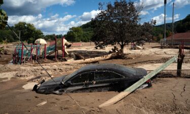 A local police car is seen half engulfed in mud