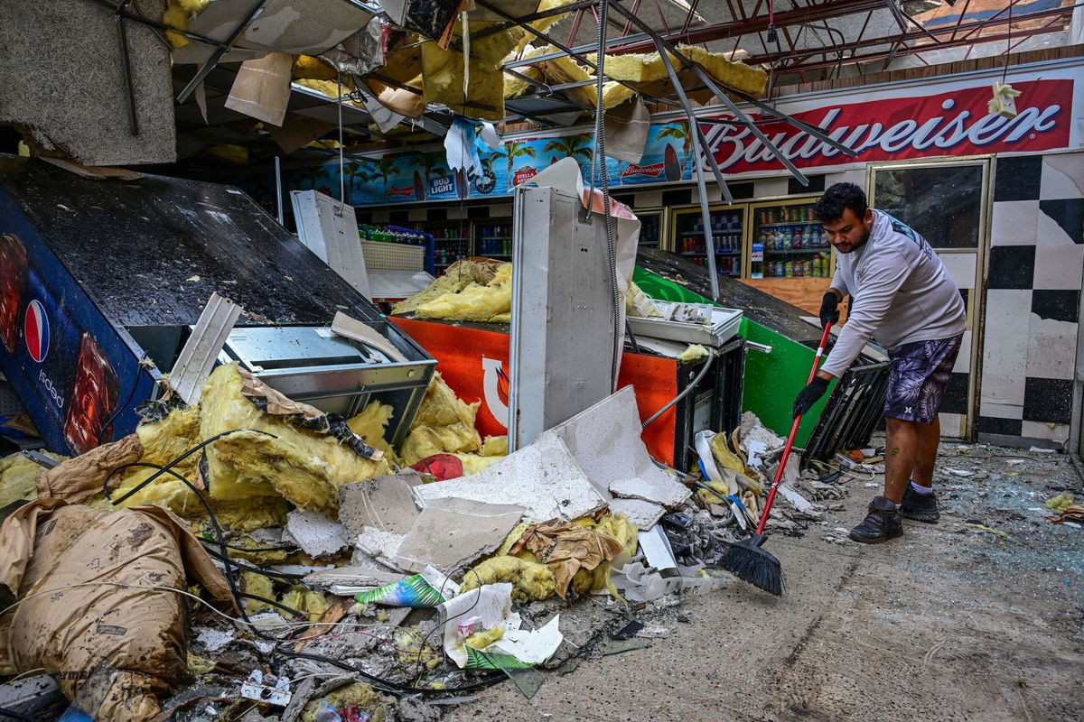 <i>Giorgio Viera/AFP/Getty Images via CNN Newsource</i><br/>A man cleans debris inside a gas station store in Lakewood Park